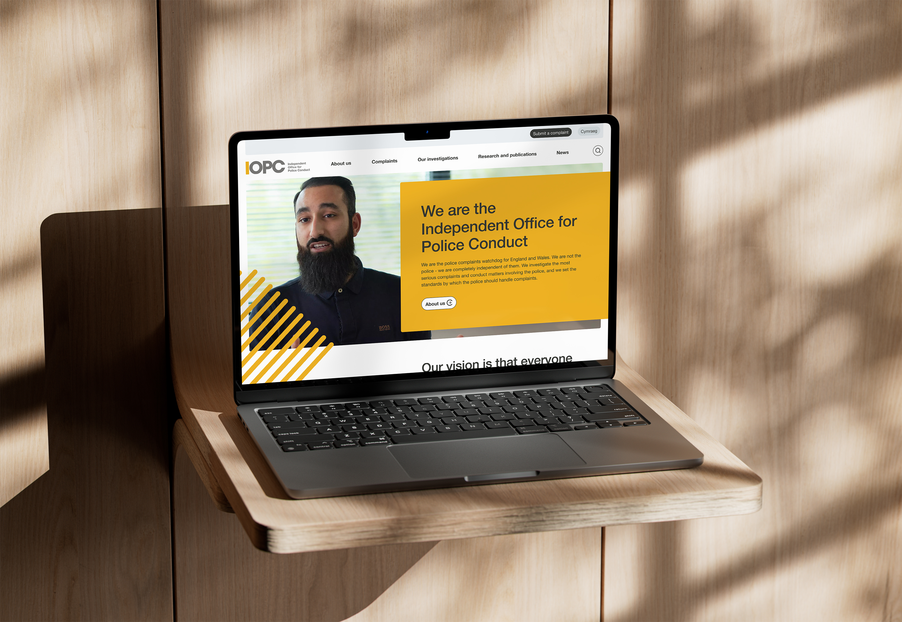 Laptop on a wooden shelf displaying the IOPC homepage with a banner introducing the Independent Office for Police Conduct.
