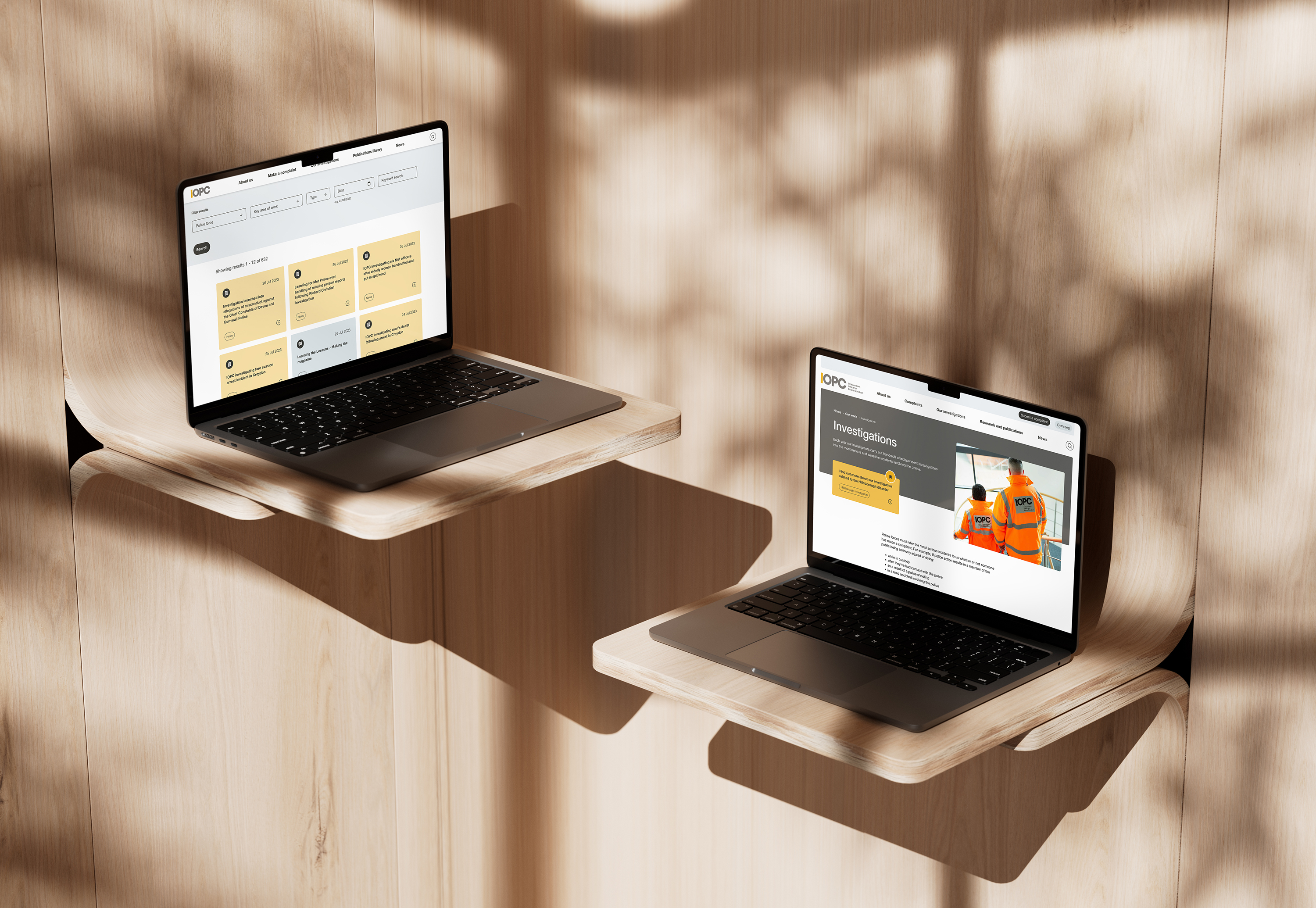 Two laptops on wooden shelves display IOPC website pages, one showing publications and the other showing investigations.