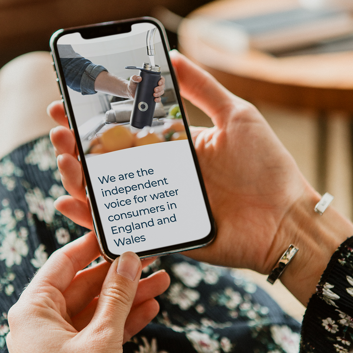 Woman holding mobile phone with CCW homepage on screen