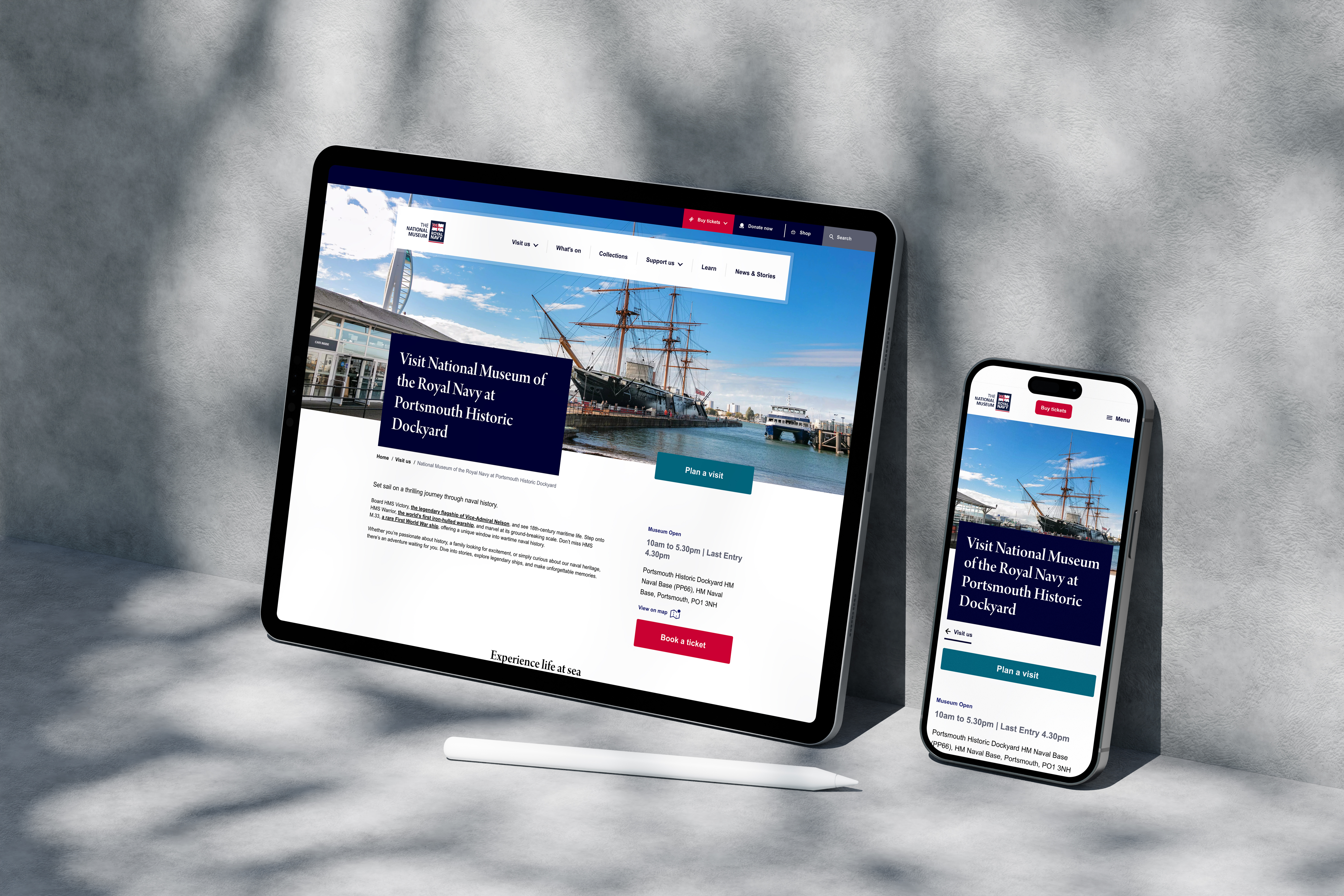 iPad and iPhone upright against a concrete wall with a visit page on both screens