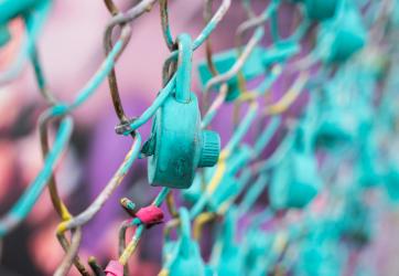 Close-up of a turquoise padlock on a wire fence